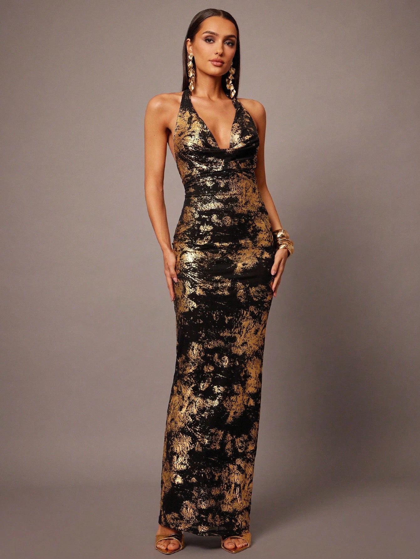 Woman wearing a black and gold sequin dress against a gray background